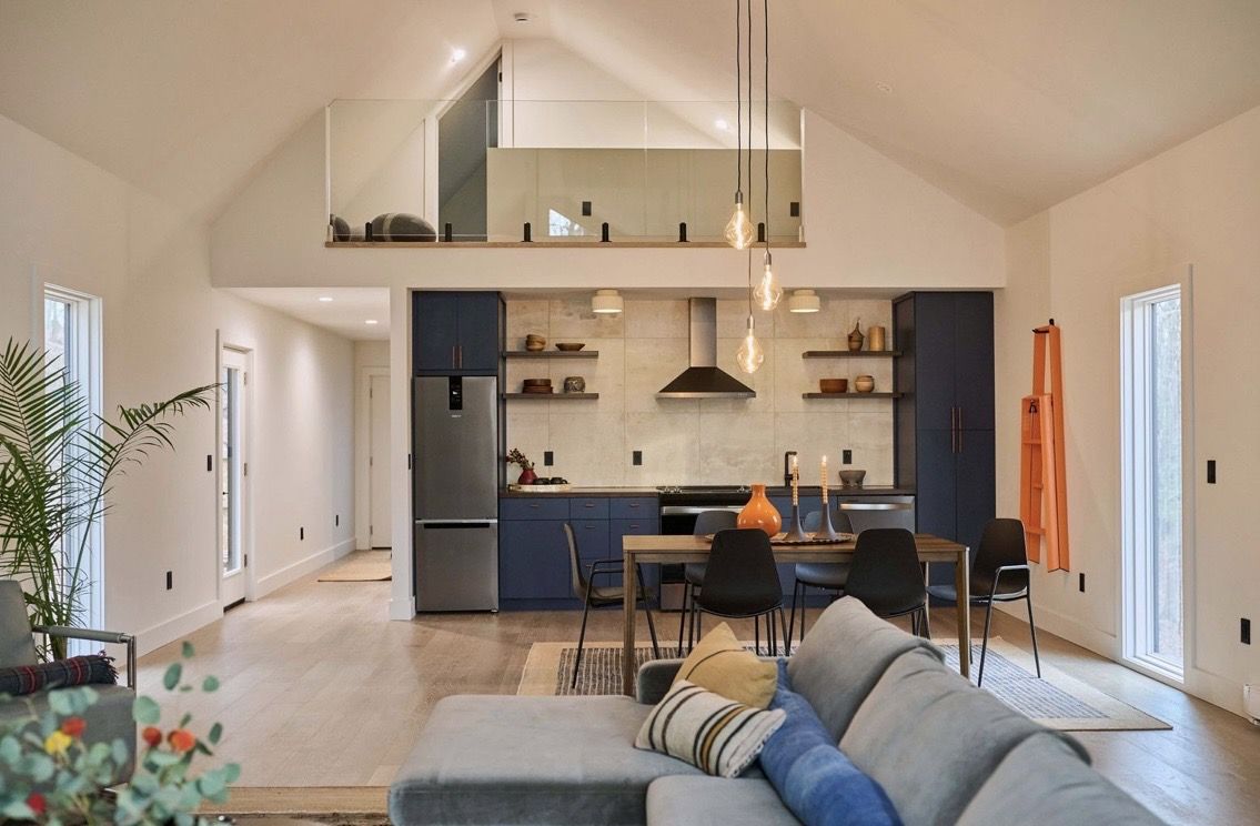 Open kitchen and living area with navy cabinets and vaulted ceiling