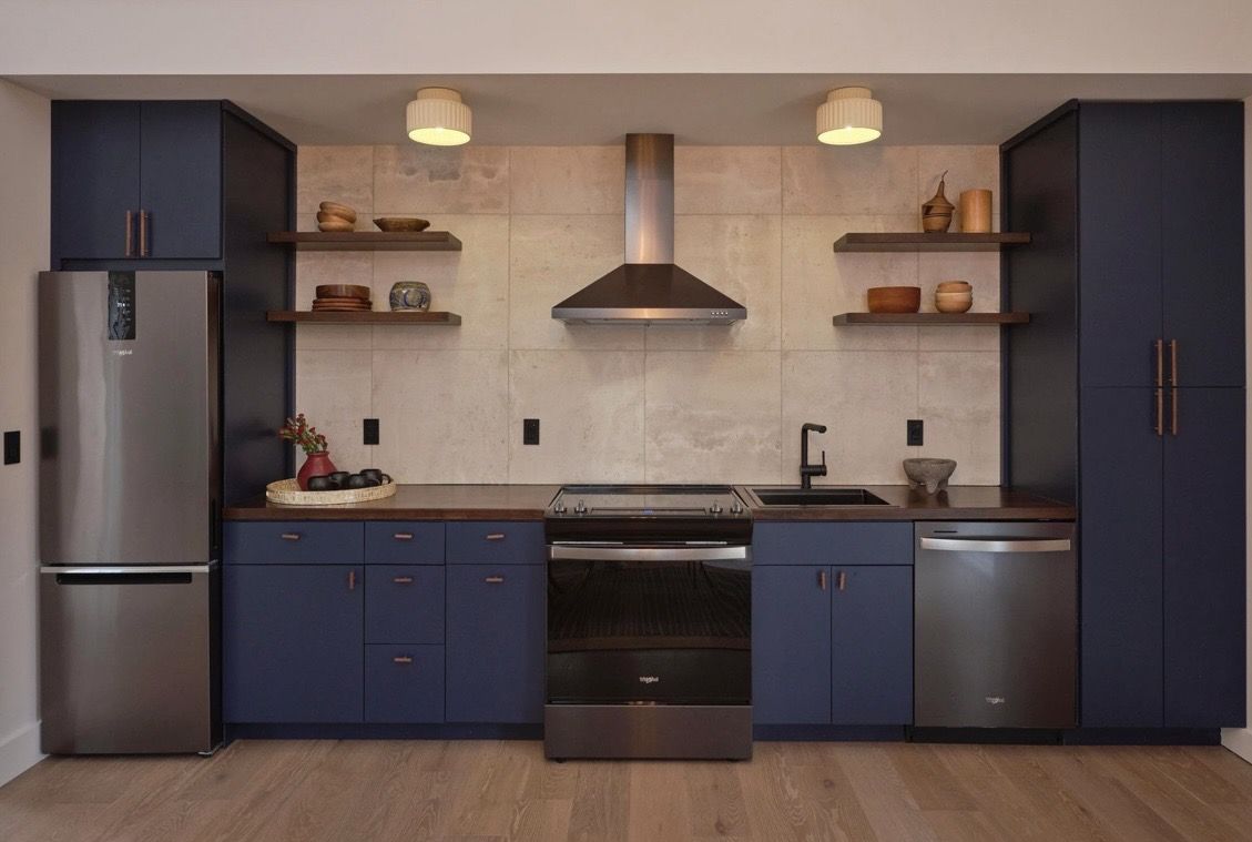 Navy kitchen with open shelving, range hood, and stainless appliances
