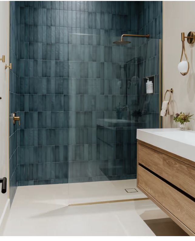 Deep blue tiled shower with brass fixtures and floating oak vanity
